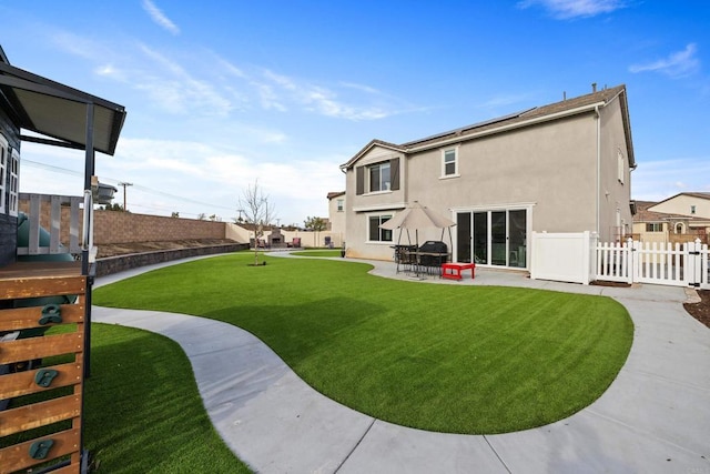 back of property with a yard and a patio