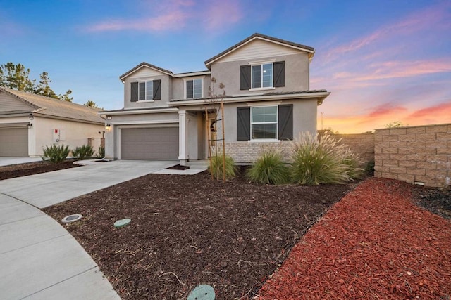 traditional-style home featuring brick siding, stucco siding, concrete driveway, an attached garage, and fence