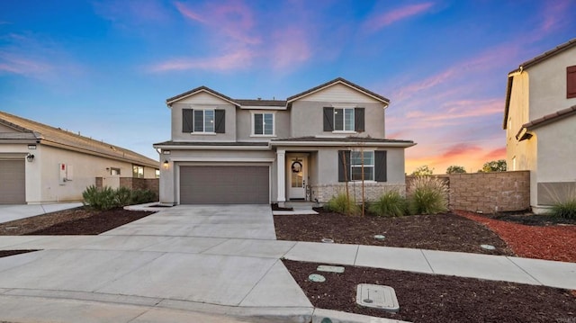 traditional-style home with stucco siding, a garage, concrete driveway, and fence