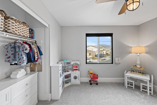 interior space featuring light colored carpet, baseboards, and ceiling fan