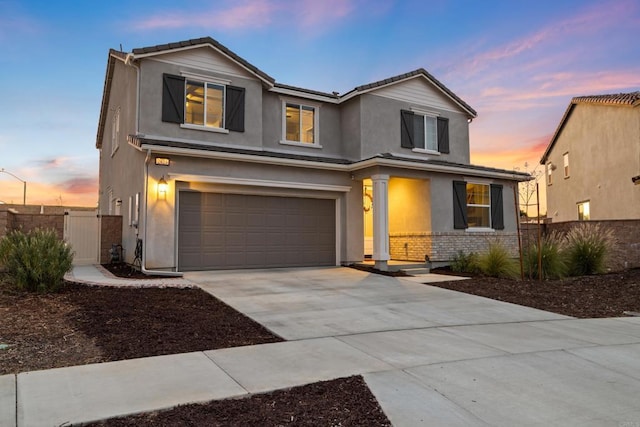 traditional home featuring stucco siding, a gate, fence, concrete driveway, and a garage