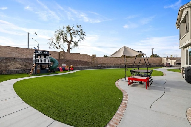 view of yard featuring playground community, a fenced backyard, and a patio area