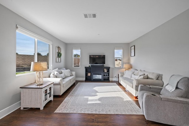 living area with dark wood finished floors, baseboards, and visible vents