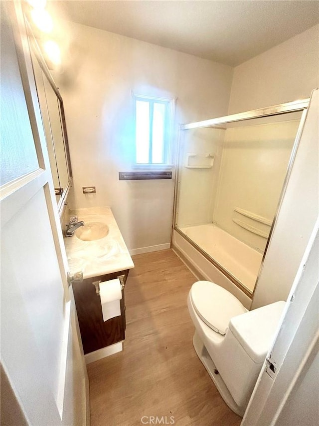 full bathroom with toilet, combined bath / shower with glass door, hardwood / wood-style floors, and vanity