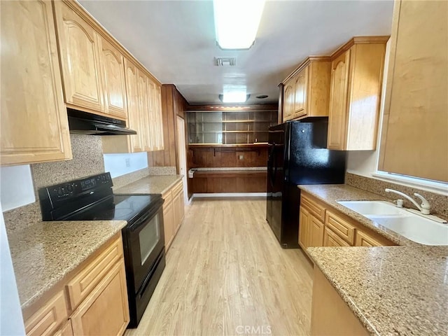 kitchen featuring black appliances, light brown cabinetry, sink, and light hardwood / wood-style flooring