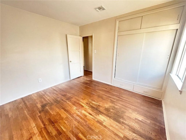 unfurnished bedroom with a closet and hardwood / wood-style floors