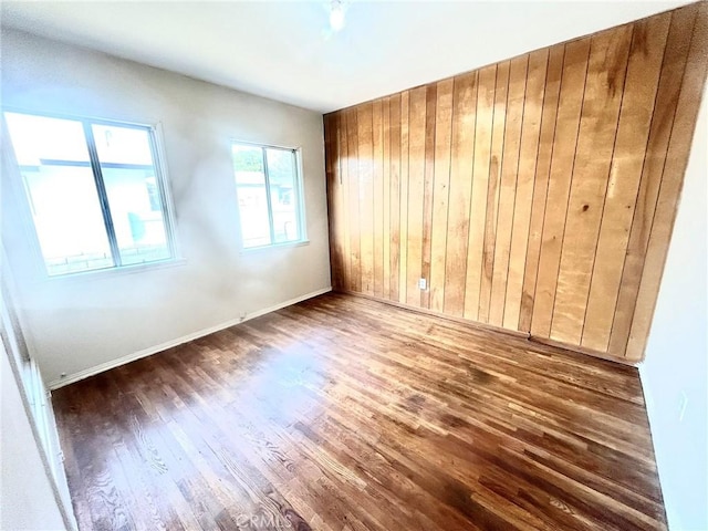 spare room featuring dark hardwood / wood-style floors and wooden walls