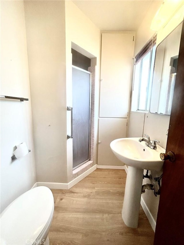 bathroom with toilet, wood-type flooring, and a shower with door