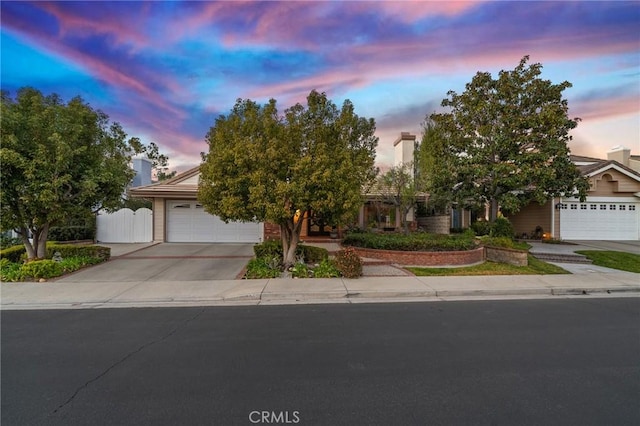 obstructed view of property featuring driveway, an attached garage, a gate, and fence