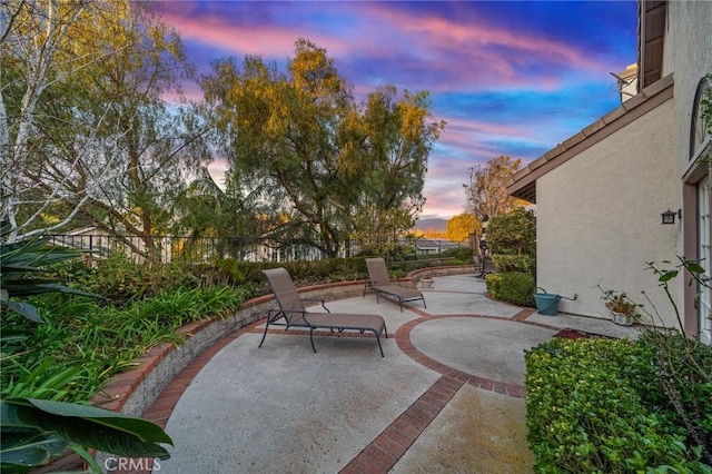 patio terrace at dusk featuring fence