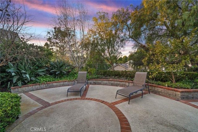 patio terrace at dusk featuring fence