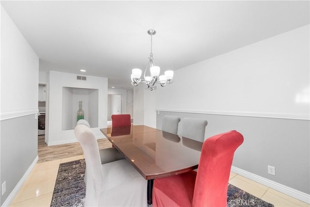 dining room with light tile patterned floors, baseboards, and an inviting chandelier