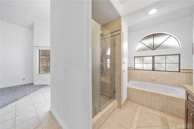 bathroom featuring baseboards, a shower stall, a bath, and tile patterned floors