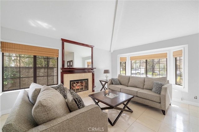 living area featuring light tile patterned floors, vaulted ceiling, a tile fireplace, and baseboards