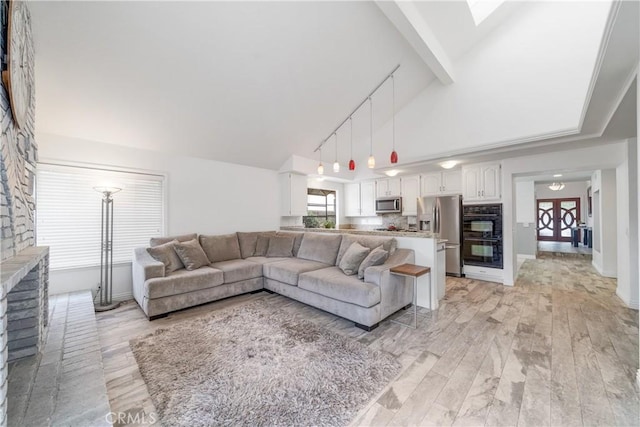 living room with high vaulted ceiling, baseboards, light wood-style flooring, and track lighting