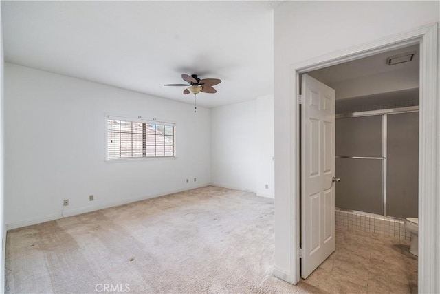 unfurnished bedroom with a walk in closet, a closet, light colored carpet, and ceiling fan