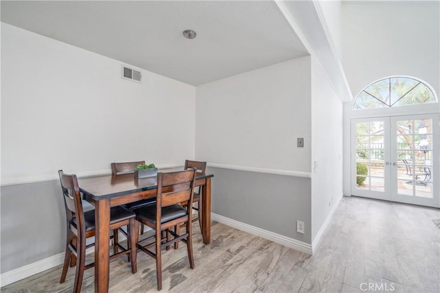 dining space with french doors, visible vents, baseboards, and wood finished floors