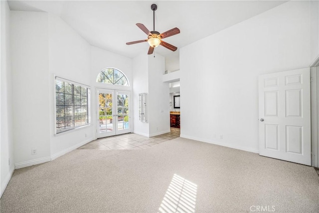 unfurnished living room featuring high vaulted ceiling, a ceiling fan, french doors, baseboards, and light colored carpet