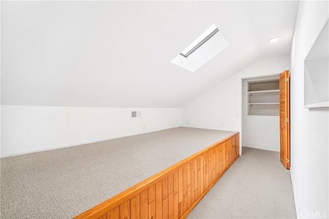 bedroom featuring lofted ceiling with skylight, light colored carpet, a closet, and visible vents