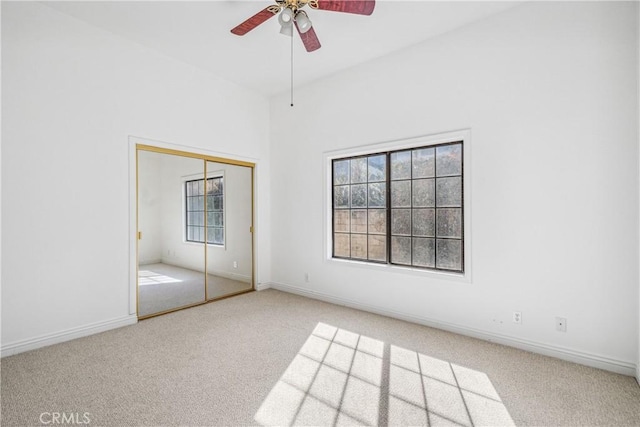 unfurnished bedroom with carpet flooring, baseboards, a closet, and ceiling fan