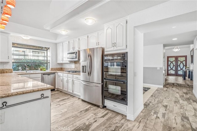 kitchen featuring plenty of natural light, white cabinetry, stainless steel appliances, and light stone countertops