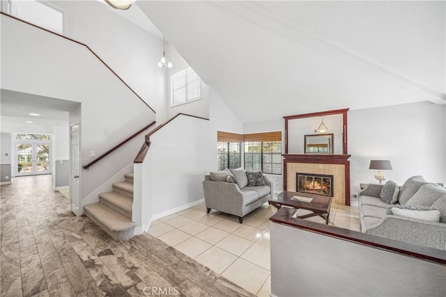 living room featuring light wood finished floors, baseboards, stairs, a fireplace, and high vaulted ceiling