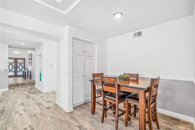 dining room featuring visible vents, light wood finished floors, baseboards, and french doors