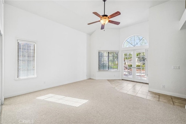 carpeted empty room featuring baseboards, high vaulted ceiling, ceiling fan, tile patterned flooring, and french doors