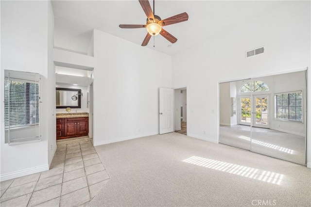 unfurnished living room featuring baseboards, visible vents, high vaulted ceiling, french doors, and light carpet