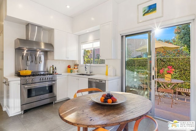 kitchen with stainless steel appliances, tasteful backsplash, wall chimney exhaust hood, white cabinets, and sink