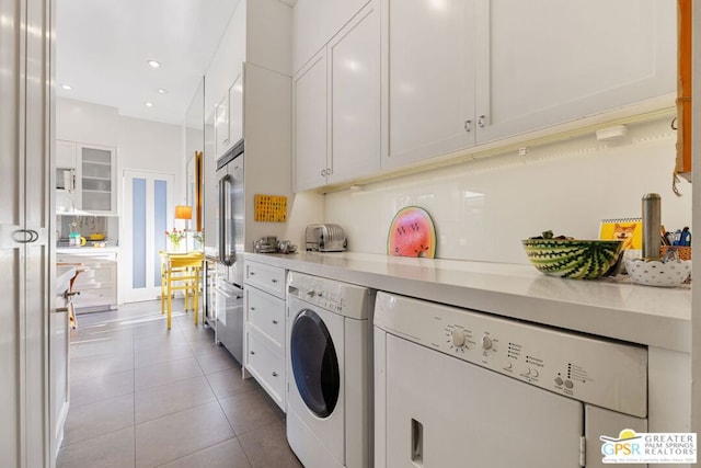 washroom with washing machine and dryer, light tile patterned flooring, and cabinets