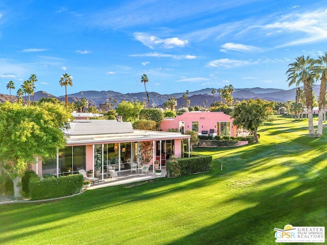 back of property featuring a mountain view, a patio area, and a yard