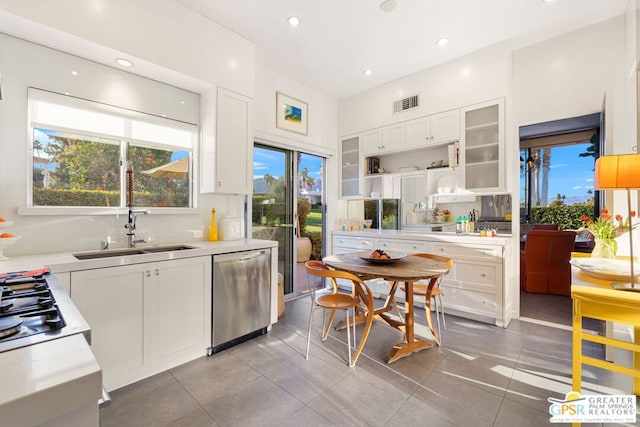 kitchen with sink, white cabinetry, stainless steel dishwasher, and light tile patterned flooring