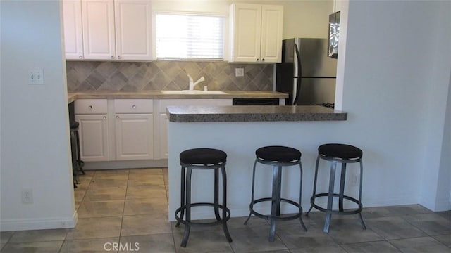 kitchen featuring white cabinetry, a breakfast bar area, and stainless steel refrigerator