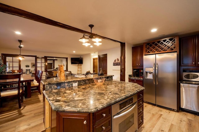 kitchen featuring decorative light fixtures, dark stone countertops, a center island, light hardwood / wood-style flooring, and stainless steel appliances