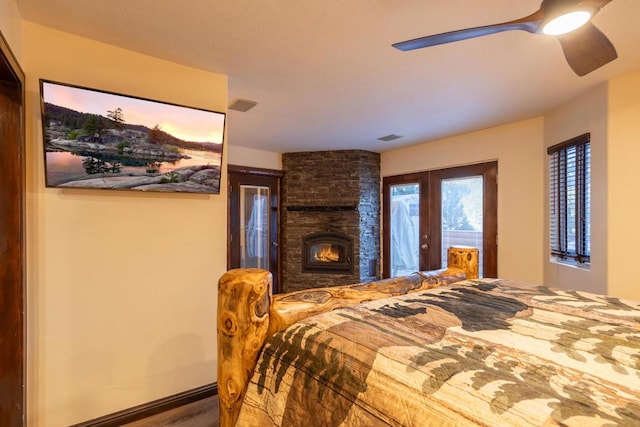 bedroom with ceiling fan, a large fireplace, and french doors