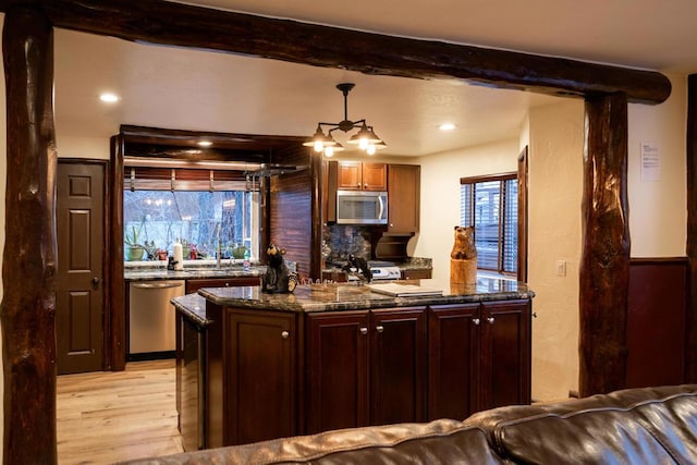 kitchen featuring light hardwood / wood-style floors, appliances with stainless steel finishes, decorative backsplash, pendant lighting, and beamed ceiling