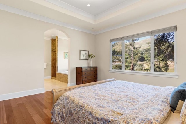 bedroom featuring crown molding, light hardwood / wood-style floors, and connected bathroom