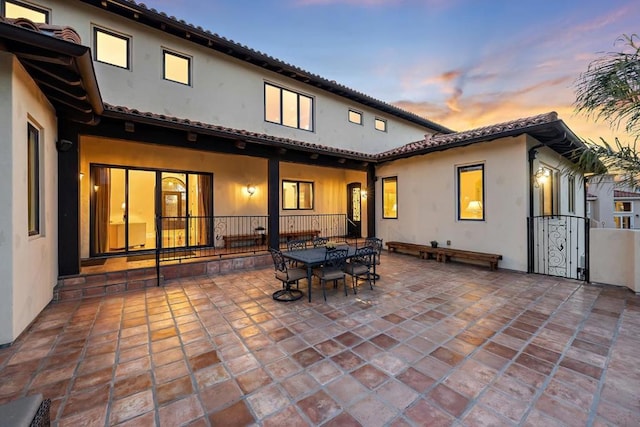 back house at dusk featuring a patio area