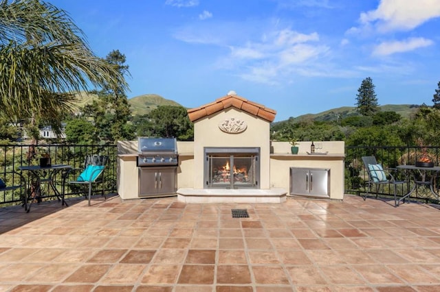 view of patio with a mountain view, an outdoor fireplace, and area for grilling