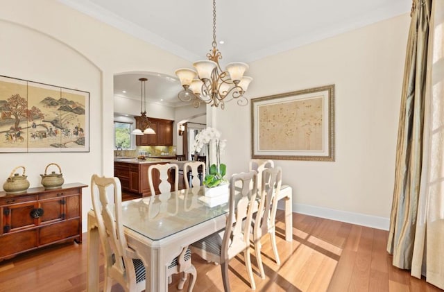 dining area featuring a notable chandelier, ornamental molding, and light hardwood / wood-style floors