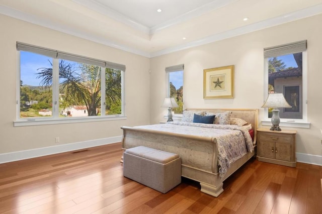 bedroom featuring hardwood / wood-style flooring, a raised ceiling, and ornamental molding