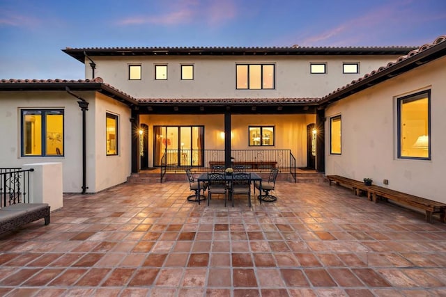 back house at dusk featuring a patio