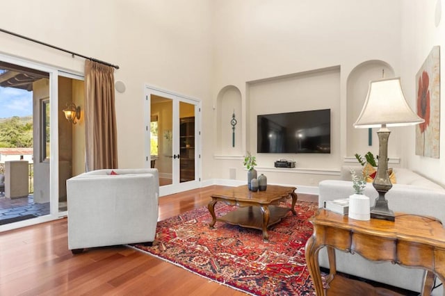 living room featuring french doors, a high ceiling, and hardwood / wood-style floors