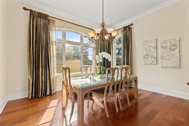 dining space with crown molding, plenty of natural light, a chandelier, and hardwood / wood-style flooring