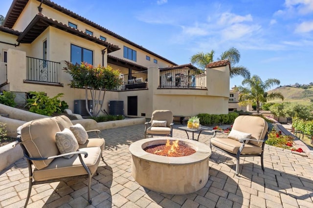 view of patio / terrace with a balcony, an outdoor fire pit, and central air condition unit