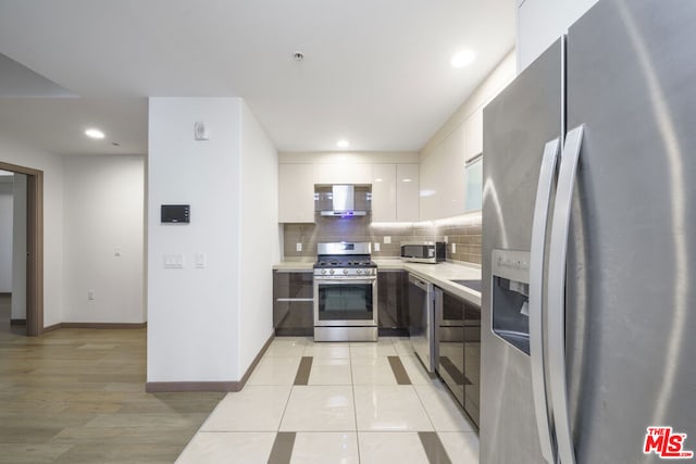 kitchen with white cabinets, backsplash, appliances with stainless steel finishes, and light tile patterned flooring