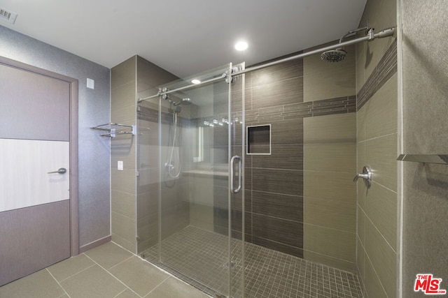 bathroom with a shower with shower door and tile patterned floors