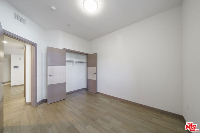 unfurnished bedroom featuring wood-type flooring and a closet