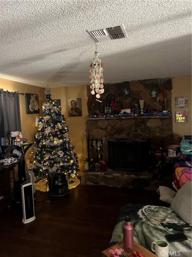 living room featuring a textured ceiling and a stone fireplace